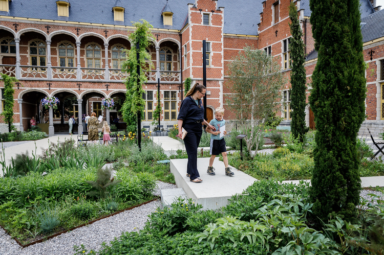 Een kind en volwassene lopen door de weelderige museumtuin.